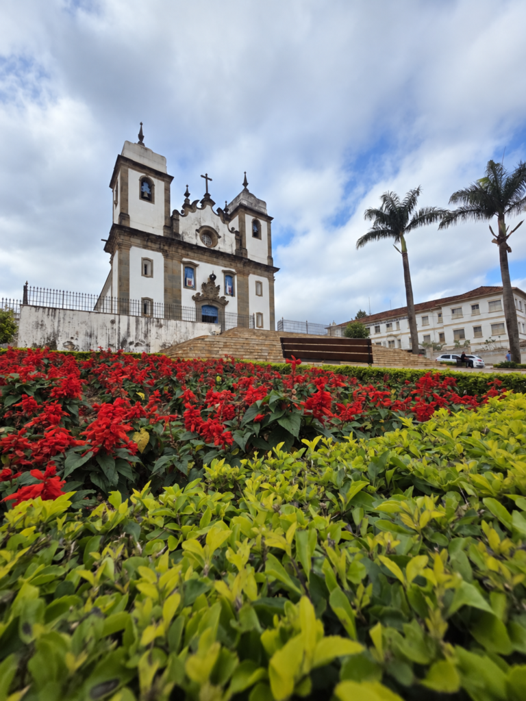 Igreja de Nossa Senhora da Conceição atrás de um jardim florido em Congonhas, Minas Gerais.