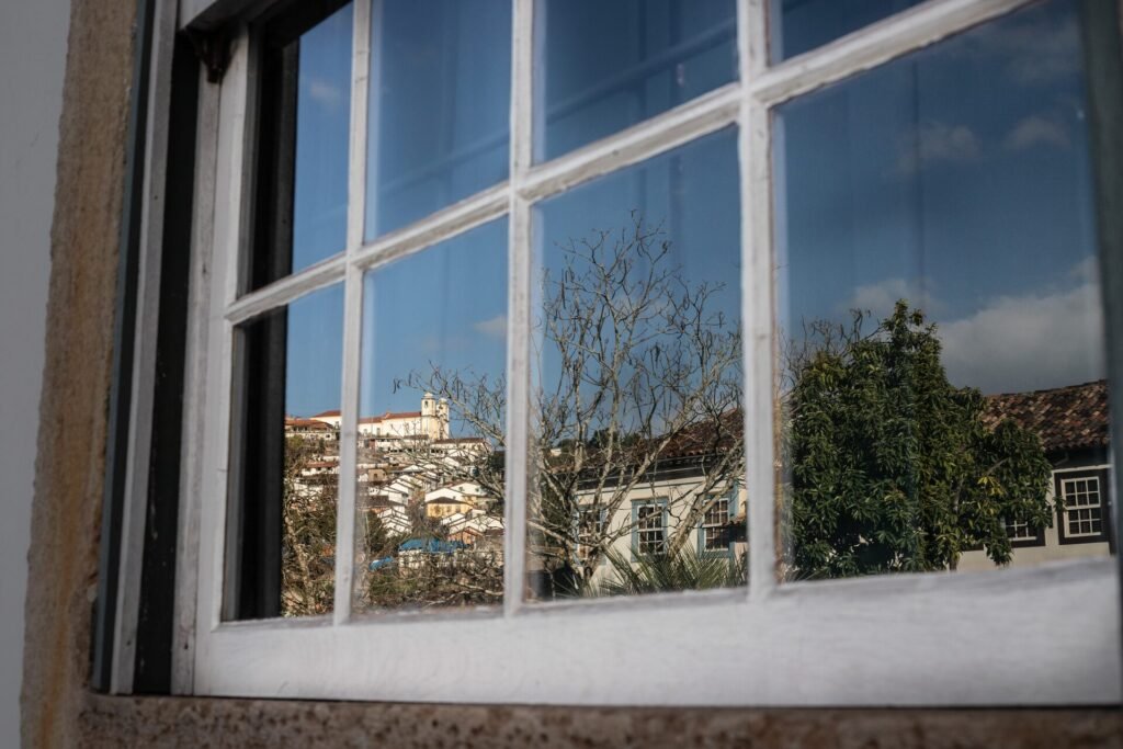 Janela colonial com moldura vermelha e veneziana verde em fachada branca