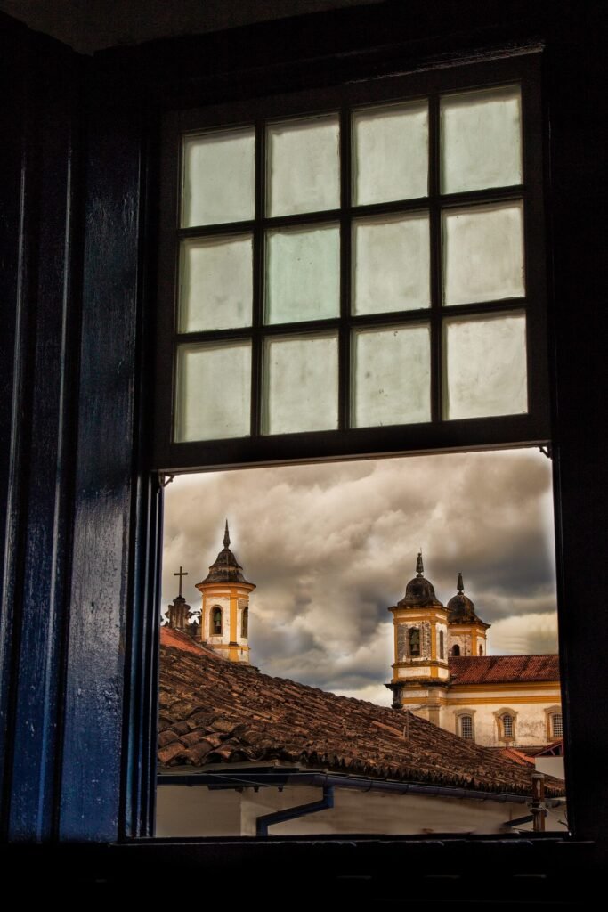 Janela colonial com moldura vermelha e veneziana verde em fachada branca