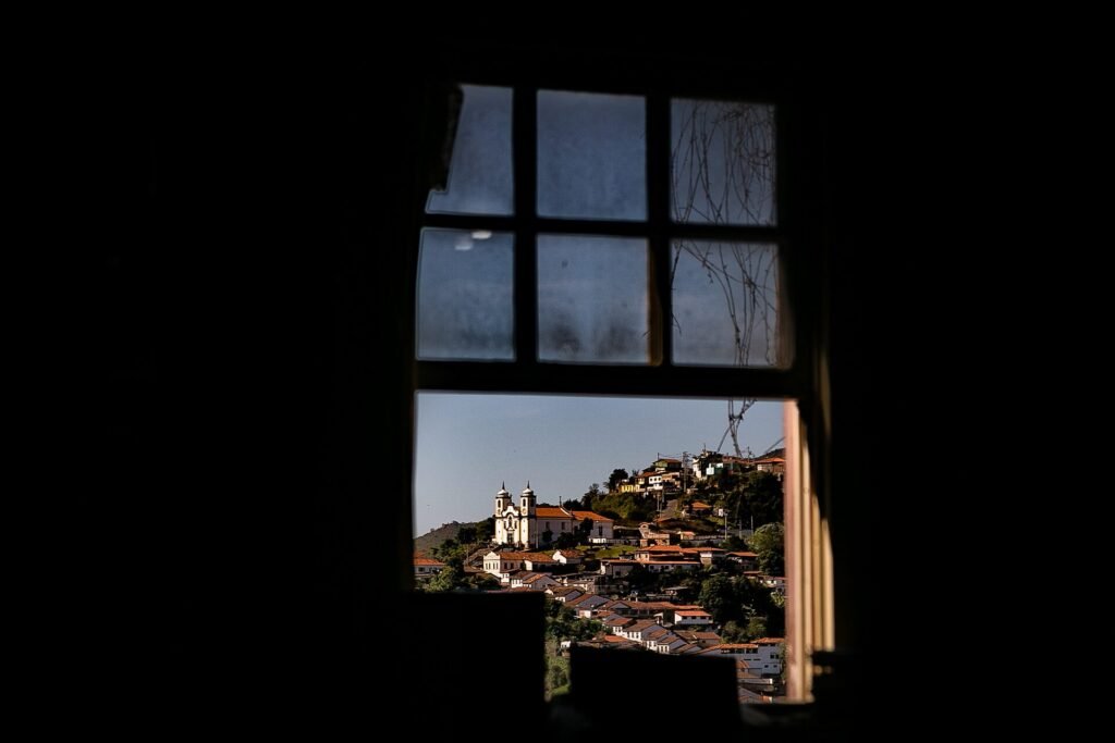 Janela colonial com moldura vermelha e veneziana verde em fachada branca