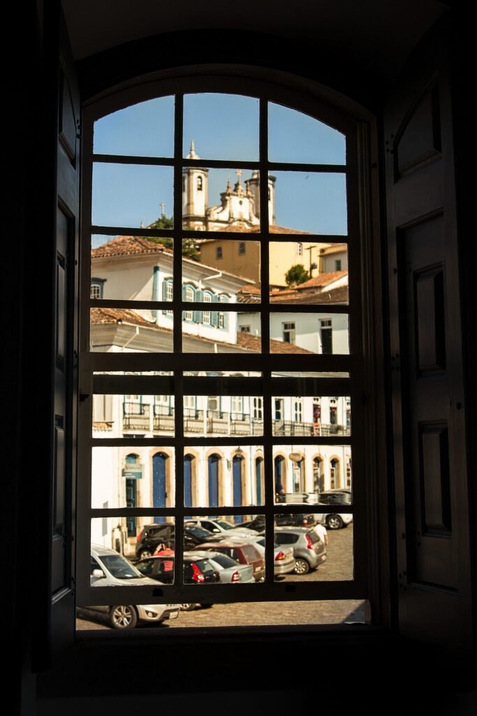 Janela colonial com moldura vermelha e veneziana verde em fachada branca