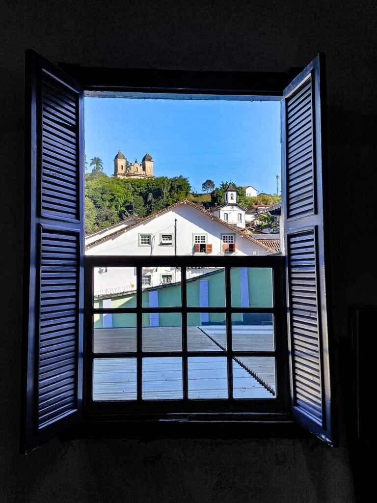 Janela colonial com moldura vermelha e veneziana verde em fachada branca