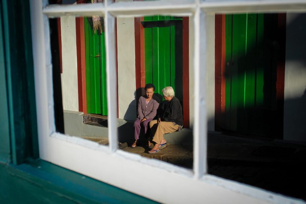 Janela colonial com moldura vermelha e veneziana verde em fachada branca