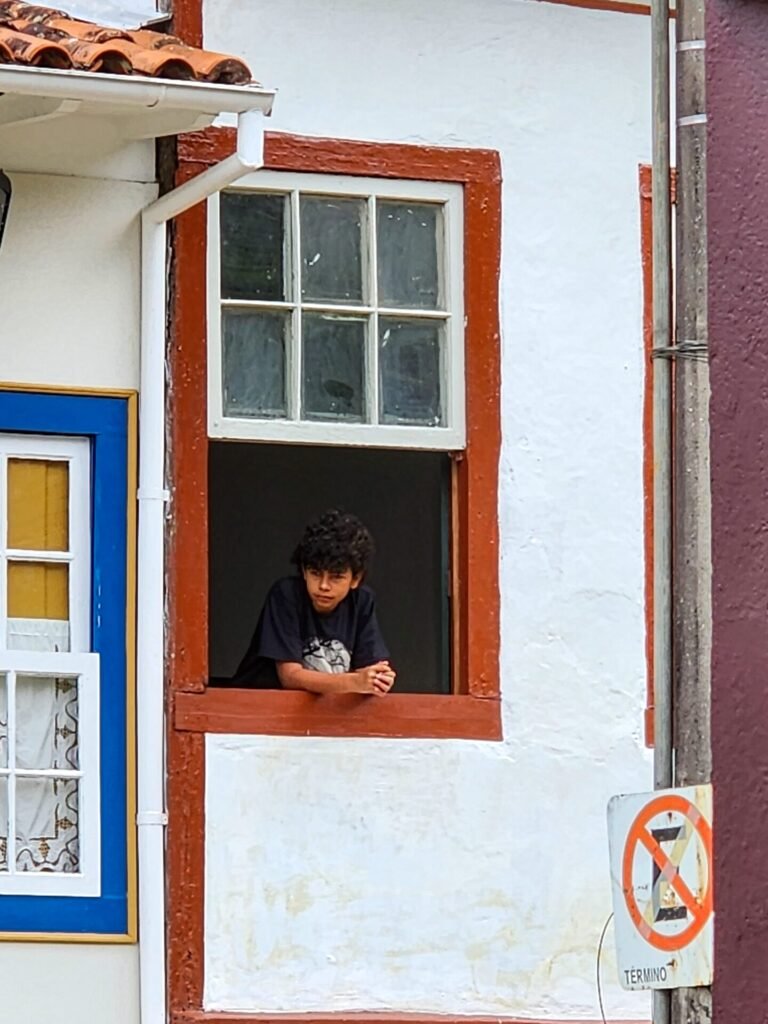 Janela colonial com moldura vermelha e veneziana verde em fachada branca