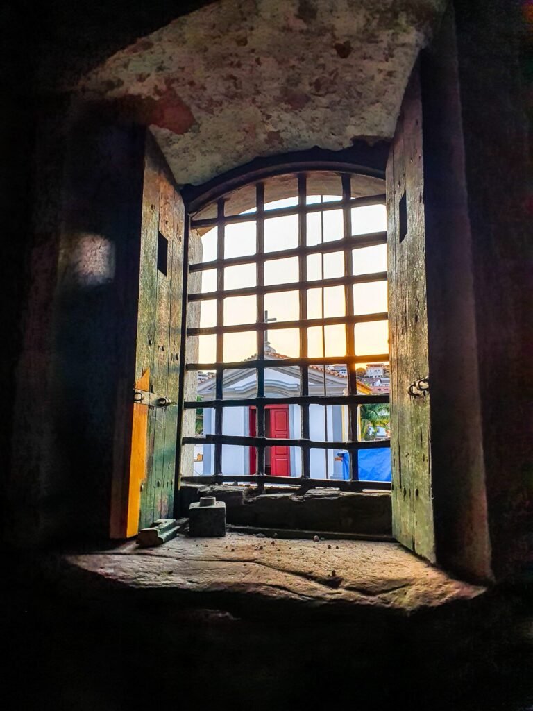 Janela colonial com moldura vermelha e veneziana verde em fachada branca