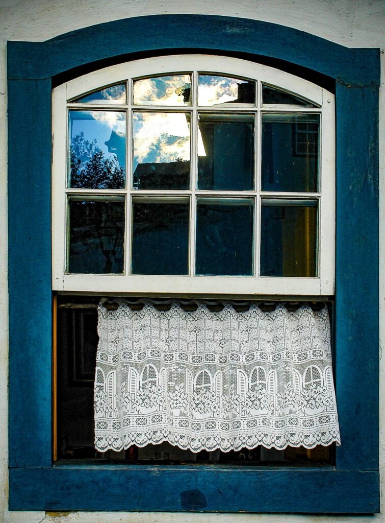 Janela colonial com moldura vermelha e veneziana verde em fachada branca