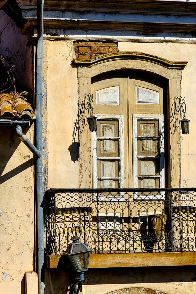 Janela colonial com moldura vermelha e veneziana verde em fachada branca